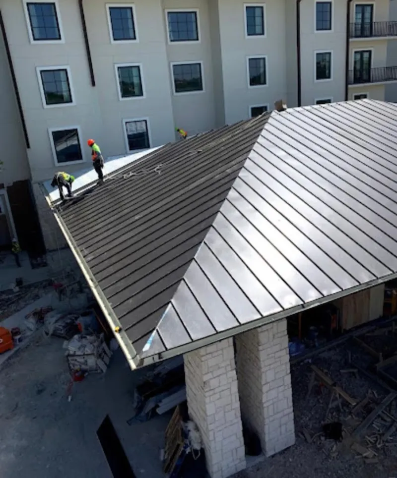 Crew installing standing seam metal roof panels on a commercial project in South Hill